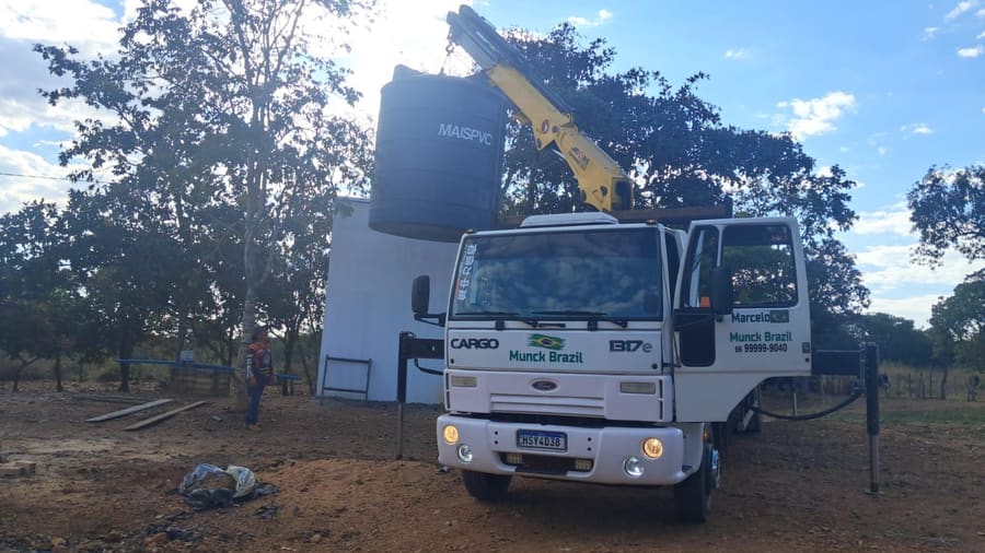 Munck içando uma caixa d’água para instalação no alto de uma estrutura