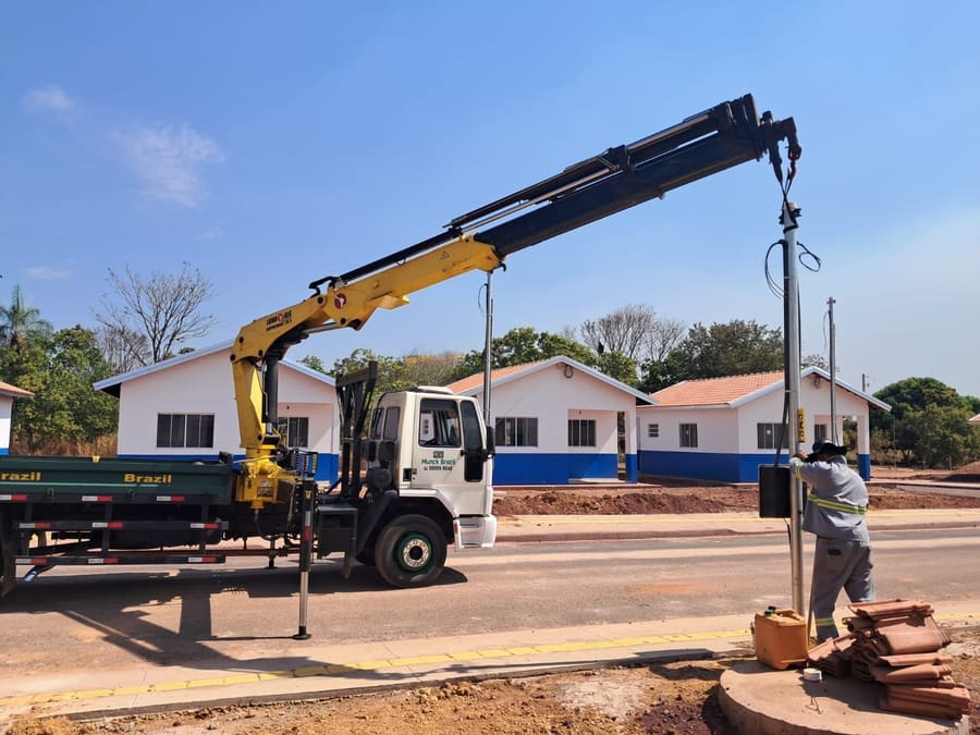 Munck içando um poste enquanto a equipe faz o posicionamento no solo