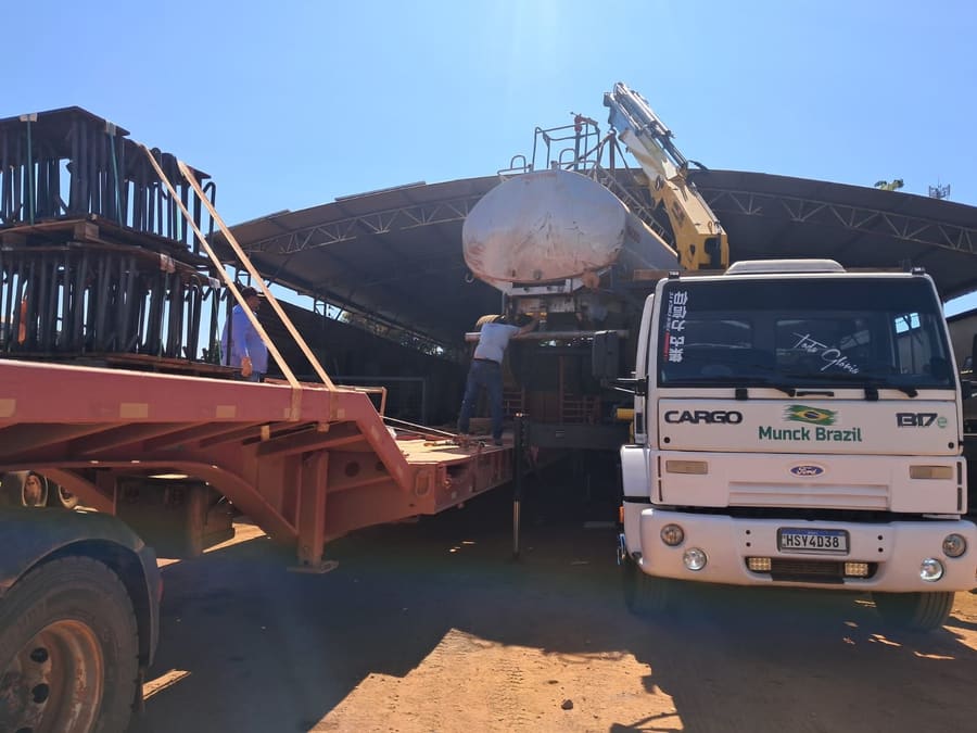 Munck movimentando um tanque metálico sob a cobertura de um galpão
